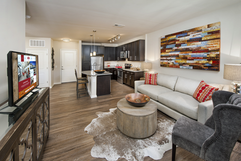 a living room and kitchen with a couch and a tv